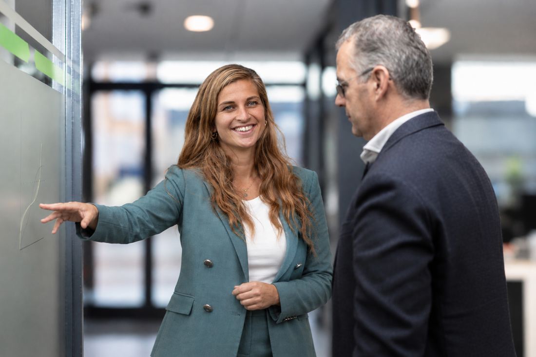 Een adviseur wijst iets aan en legt het uit aan een directeur