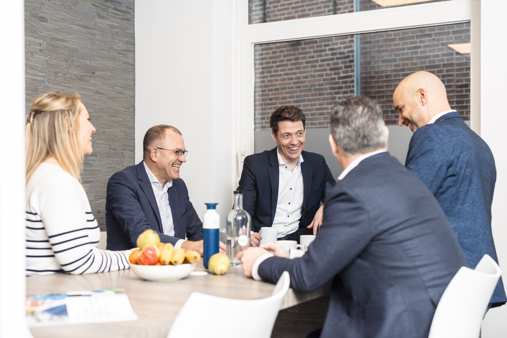 Collega's lachen en praten rond een tafel
